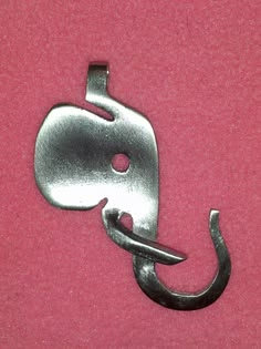 a metal hook with an elephant head on it's end and a pink background