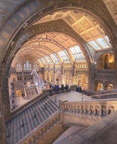 people are walking up and down the escalator in an old building with arched ceilings