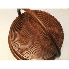 an intricately carved wooden bowl on a white surface