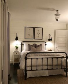 a bedroom with white walls and black iron bed frame