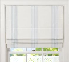 an open window with roman blinds and white curtains