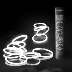 a tube of glue sitting next to some neon rings and a roll of tape on a black background