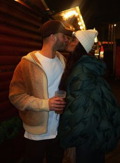 a man and woman kissing each other in front of a building at night with lights on