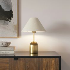 a lamp on a dresser next to a painting