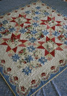 a quilt is laying on the bed with blue sheets and red and white stars around it