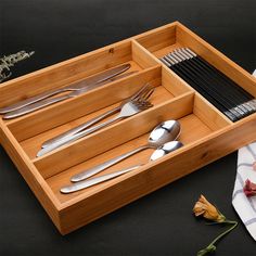 a wooden tray with utensils and spoons in it