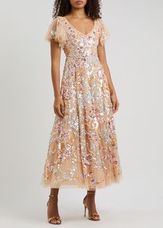 This Needle & Thread gown is crafted from tulle and features a ruffled V-neck, signature kisses embroidery, floral sequin embellishments, and a curved hem. It is fully lined and has a concealed zip fastening at the back. The gown is made of 100% recycled polyester and should be dry cleaned. The length from shoulder to hem is 53.5 inches/136cm. It has a slim fit bodice and a flared skirt. The gown is embellished, embroidered, and has a ruffle. Gown Gold, Skirt Model, Tulle Gown, Embroidery Floral, Dress Home, Needle Thread, Flared Skirt, Party Dresses For Women, Ladies Party