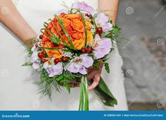 a bridal bouquet with orange and purple flowers on the bride's wedding day