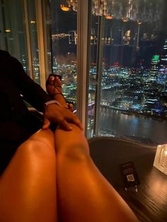 a woman's legs are shown with the city lights lit up in the background