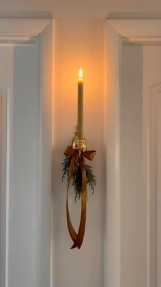 a candle is hanging on the wall next to a door with a ribbon around it