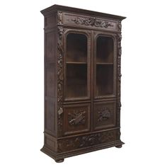 an ornate wooden cabinet with glass doors and carvings on the front, in dark brown