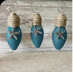 three blue christmas ornaments hanging from twine with starfishs on each ornament