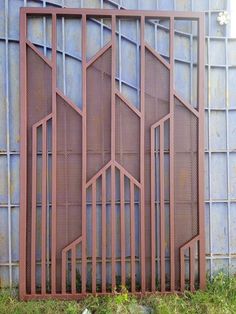 an iron gate is shown in front of a blue metal wall with grass growing on the ground