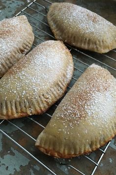 four pastries cooling on a rack with powdered sugar sprinkled on them