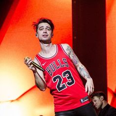 a male in a red jersey is holding a bottle