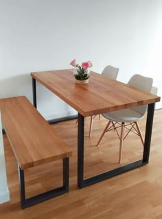 a wooden table with two white chairs and a flower pot on top of the table