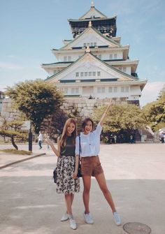 two women standing in front of a tall building with a clock tower on it's side