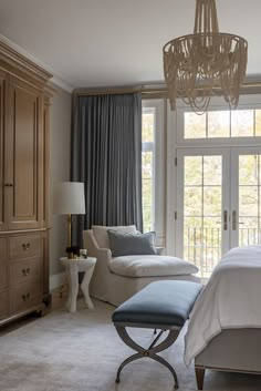 a bedroom with a chandelier hanging from the ceiling next to a bed in front of a sliding glass door