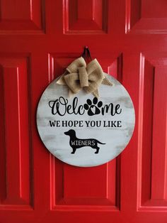 a welcome sign hanging on a red door that says, welcome we hope you like wieners