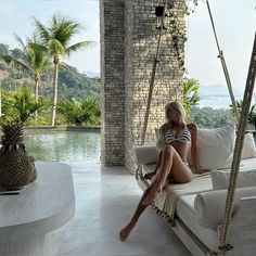 a woman sitting on a white couch next to a pool