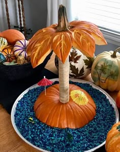 pumpkins and gourds are sitting on a table with blue gravel in the center