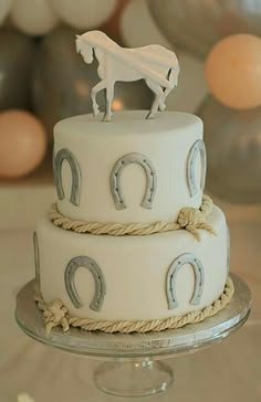 a three tiered cake with a horse on top and horseshoes around the edges