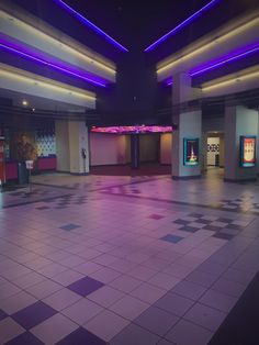 an empty room with checkered tile floors and purple lighting on the ceiling is lit by blue lights