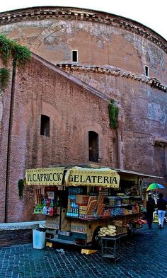 an old building with a fruit stand in front of it on a cobblestone street