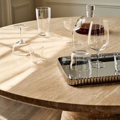 a wooden table topped with wine glasses and an empty tray on top of the table