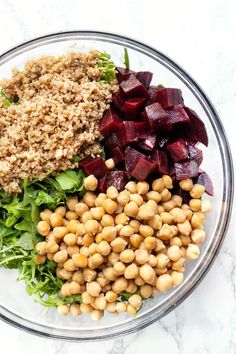 beets, lettuce, and chickpeas in a glass bowl on a marble surface