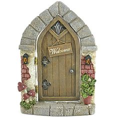 a small statue of a welcome sign in front of a door with plants and flowers