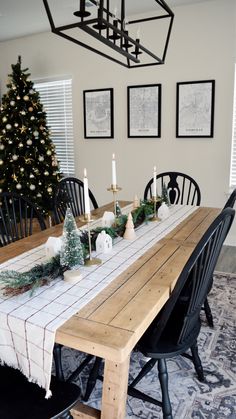 a dining room table decorated for christmas with candles and greenery on the table top