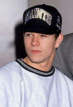 a young man wearing a saints baseball cap