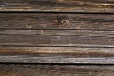 an old wooden wall with peeling paint and chipped wood grains, as well as nails