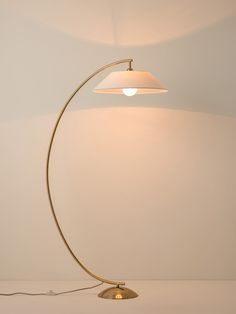 a floor lamp with a white shade on it's side and a cord attached to the base