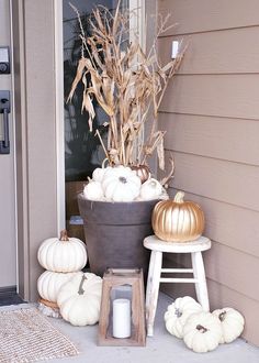 the front porch is decorated for fall with white pumpkins and cornstatches