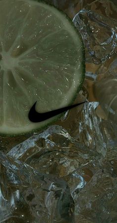 a lime with a black nike logo on it sitting in some ice cubes next to a slice of lime