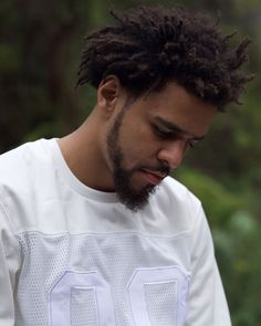 a man with dreadlocks looking down at his cell phone