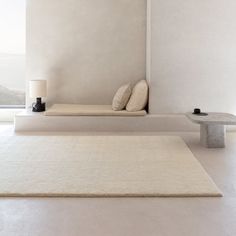 a white room with two benches and a rug on the floor in front of it