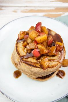 a stack of pancakes topped with fruit and syrup