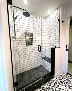 a walk in shower sitting next to a white door and black tile on the floor