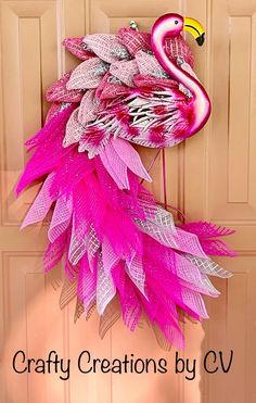 a pink flamingo wreath hanging on a door with the words crafty creations by cv