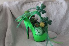 a green shoe decorated with shamrocks, coins and ribbons on a white sheeted surface