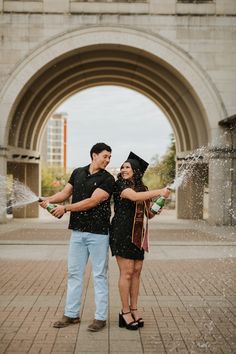 a man and woman are standing in front of an archway with water spraying from their hands