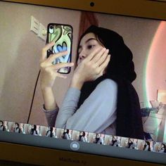 a woman is holding her cell phone up to her face and looking at the screen