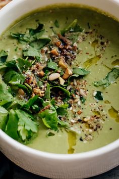 a white bowl filled with green soup and garnished with nuts