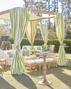 an outdoor seating area with green and white striped drapes on the side of it