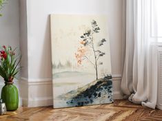 a painting sitting on top of a wooden floor next to a vase filled with flowers