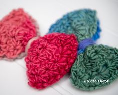 three crocheted hearts sitting on top of a white table next to each other