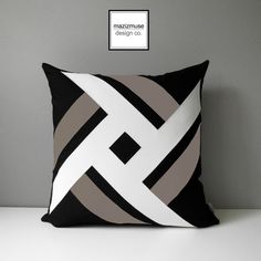 a black and white pillow sitting on top of a table next to a gray wall